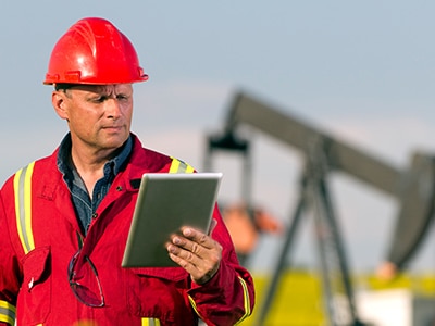 Man with clipboard in front of oil pump