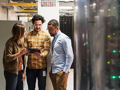 three people in server room looking at tablet