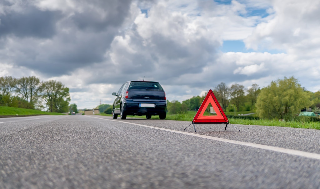 SUV on side of road with triangle hazard sign