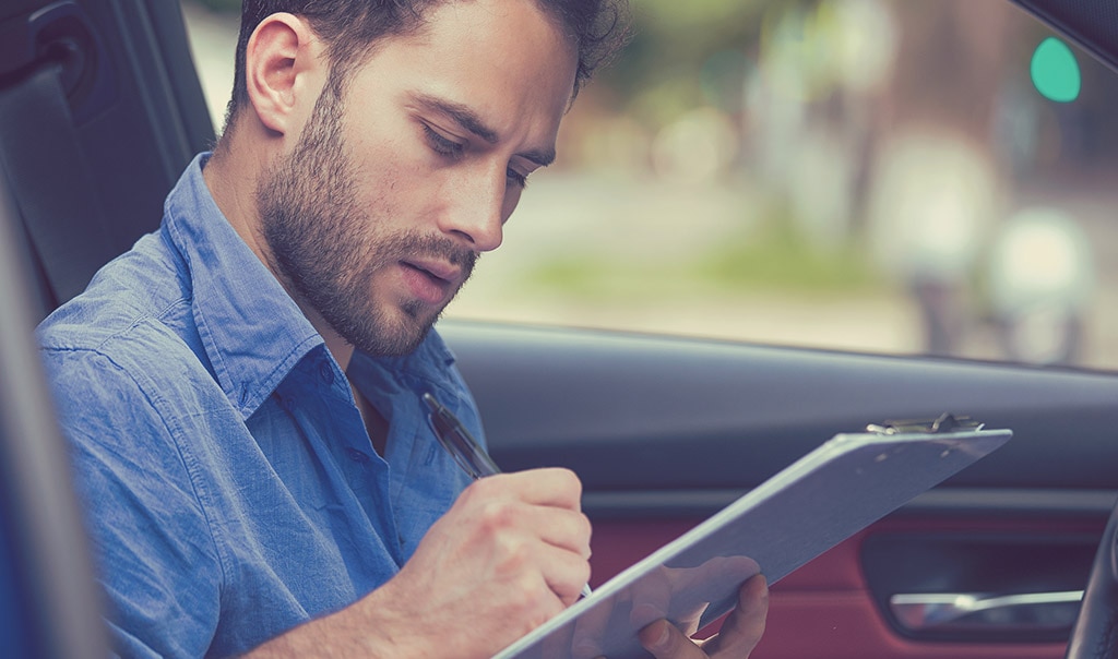 man writing on clipboard