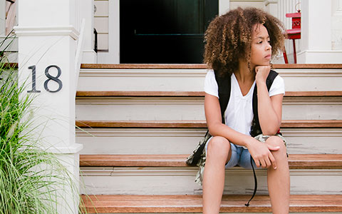 girl with curly hair, white tshirt and backpack sitting on stairs