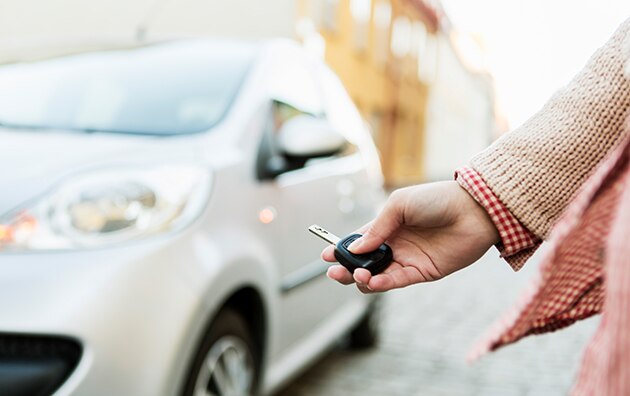 holding car keys in front of a white car