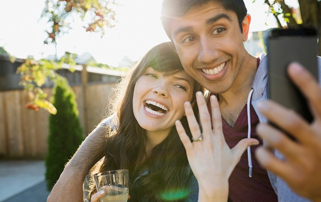 Engaged couple showing holding up a ring